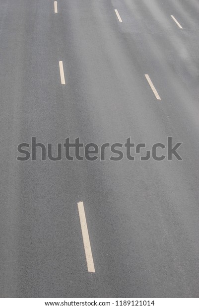 view from\
above on an asphalt road or highway with dividing stripes, outgoing\
perspective, soft gray\
background
