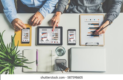 View From Above.One On One Meeting.Businessmen Sitting At Desk And Working.On Table Smartphones And Digital Tablet With Graphs,charts And Diagrams On Screen,closed Laptop,houseplant And Notebook.