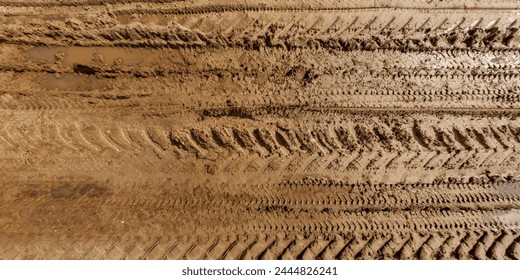 view from above on texture of wet muddy road with puddle and tractor tire tracks in countryside