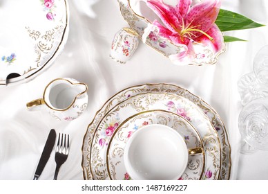 View from above over a table arrangement of a luxury porcelain dinnerware with golden hand painted floral design. 