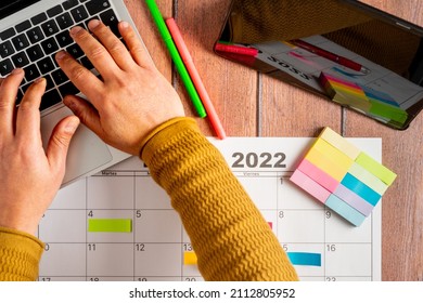 View From Above Of A Person Writing Notes On His Laptop With A Digital Tablet And Calendar Of The Year 2022. Colorful Post-it Notes To Highlight The Activities To Be Carried Out. Concept Of Time