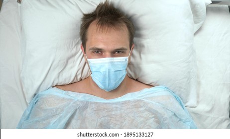 View From Above. Portrait Of A Man In A Medical Mask Lying On A Bed In A Hospital