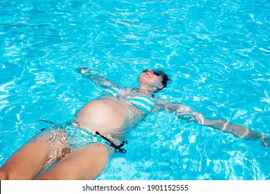 Blick von oben auf schwangere Frau schwimmen im Schwimmbad mit Händen gestreckt