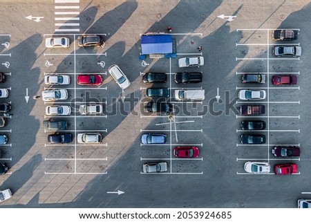 A view from above to the process of car parking. Heavy traffic in the parking lot. Searching for spaces in the busy car park. Parking advice. Cruising for parking in busy business center.