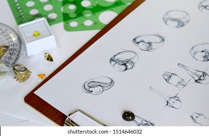The view from above, sketches, ornaments, rings and various accessories placed on the work desk.