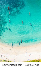 View from above, stunning aerial view of a beautiful tropical beach with white sand and turquoise clear water, long-tail boats and people sunbathing, Banana beach, Phuket, Thailand.
