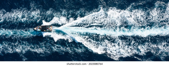 View from above, stunning aerial view of a boat cruising on a blue water creating a wake. Costa Smeralda, Sardinia, Italy. - Powered by Shutterstock