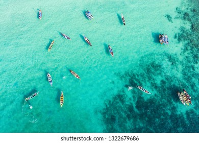 View from above, stunning aerial view of a large group of traditional longtail boats floating on a turquoise and clear sea that bathes the tropical Freedom beach in Phuket, Thailand. - Powered by Shutterstock