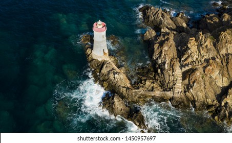 View From Above, Stunning Aerial View Of An Old And Beautiful Lighthouse Located On A Rocky Coast Bathed By A Rough Sea. Faro Di Capo Ferro, Porto Cervo, Sardinia, Italy.