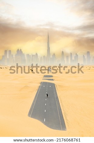 View from above, stunning aerial view of a person walking on a deserted road covered by sand dunes with the Dubai Skyline in the distance. Dubai, United Arab Emirates.