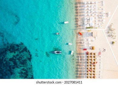 View from above, stunning aerial view of some bathing establishments on a white sand beach bathed by a turquoise water during a beautiful sunset. Cala di volpe, Costa Smeralda, Sardinia, Italy.