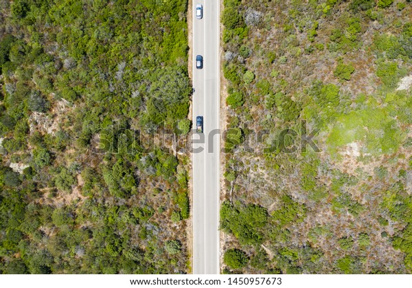 View\
from above, stunning aerial view of some cars that runs along a\
road flanked by a green forest. Sardinia,\
Italy.