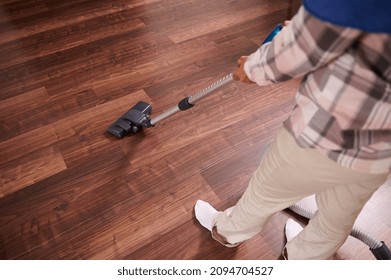 View From Above Of A Unrecognizable Woman, Housewife, Housekeeper Vacuuming Floor On The Living Room. Focus On Vacuum Cleaner. Close-up