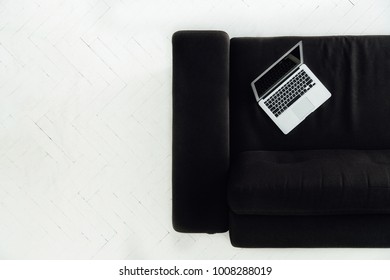 View From Above Of White Laptop Standing On Black Couch, White Floor. Minimalism.