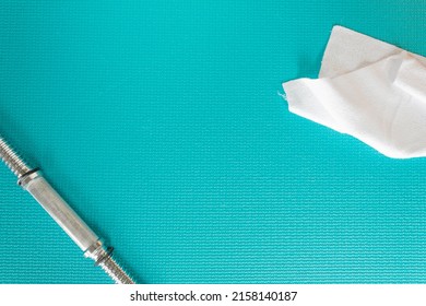 View From Above Of A White Sweat Towel And Weight Bar On A Blue Mat Green Exercise Mat With Copy Space