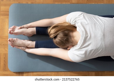 View From Above Of Woman Stretching Hamstring Muscles Holding Her Feet With Hands.