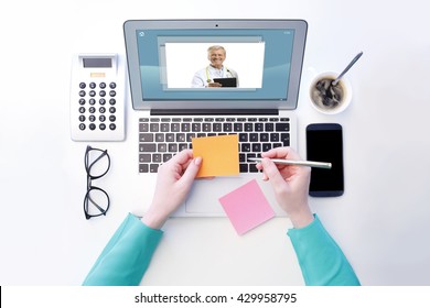 View From Above Of Young Woman Sitting At Desk In Front Of Laptop And Having Video Chat With Senior Male Doctor. Isolated On White Background.