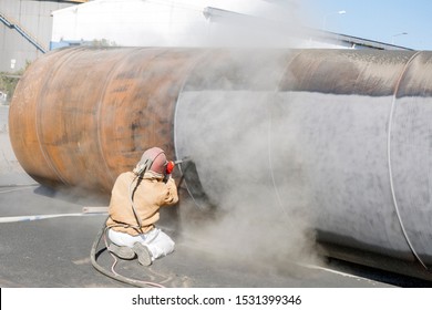 View of the abrasive blasting (sandblasting, grit blasting or shot blasting) to steel large pipe. Sandblasting is an extremely useful procedure in a broad array of applications and industries.