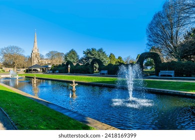 A view across ornate gardens towards the Saint Mary and Saint Nicolas Church in Spalding, Lincolnshire on a bright sunny day