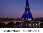 View across the river of the Eiffel tower dressed in European flag lighting for the French presidency