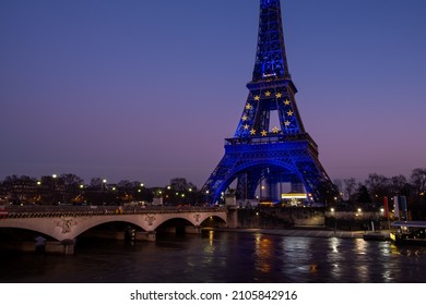 View across the river of the Eiffel tower dressed in European flag lighting for the French presidency