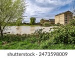 A view across the River Great Ouse towards the London Road causeway and old Victorian Millhouse in St Ives, Cambridgeshire, England.