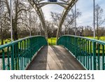 A view across the Suspension bridge over the River Great Ouse towards the island bank in Bedford, UK on a bright sunny day