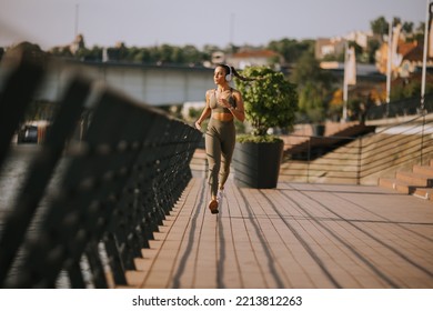 View at active young beautiful woman running on the promenade along the riverside - Shutterstock ID 2213812263