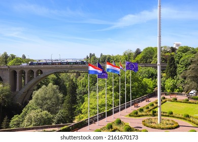 View of the Adolphe Bridge in Luxembourg City. Flags of Luxembourg and the European Union fly in the foreground.