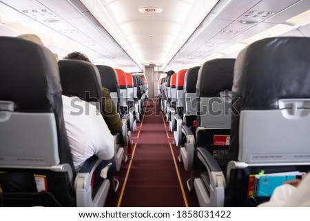 View of Airplane Aisle  with the Passengers Sitting on their Seats