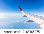 View from the airplane window at a beautiful cloudy sky and the airplane wing. Earth and sky as seen through window of an airplane.