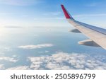 View from the airplane window at a beautiful cloudy sky and the airplane wing. Earth and sky as seen through window of an airplane.