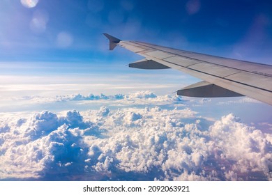 View from the airplane window at a beautiful cloudy sky and the airplane wing. Earth and sky as seen through window of an airplane.