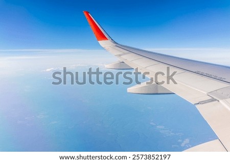 View from the airplane window at a beautiful cloudy sky and the airplane wing. Earth and sky as seen through window of an airplane.