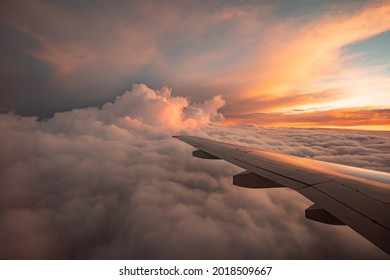 The view from the airplane window to the clouds and sunset. Airplane wing above thick pink and orange clouds. Wonderful breathtaking view. - Powered by Shutterstock