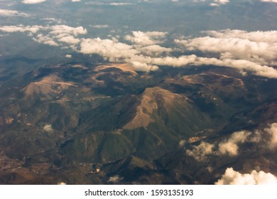 View from airplane window at mountains and white clouds flying above Montenegro. Aerial perspective. Aerial view of mountain landscape from an airplane window.