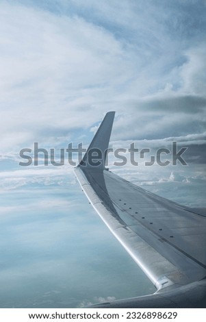 View of airplane wing, blue skies during landing. Airplane window view. Earth and sky as seen through window of an airplane. Top view from inside window airplane of a beautiful sky and wing. clouds