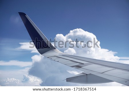 View Of Airplane Wing From Cabin Window When The Airplane Flying High Above The Cloudy Sky. Traveling With Airline. Side View From Inside