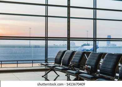 View of airport interoir, empty bench chairs in the departure hall during sunrise. Airplane and building background. Travel and transportation concept