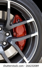 View of the aluminum wheel of a sport car with red brake caliper.
Red brake caliper.