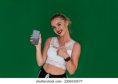 View Of Amazing Beautiful Young Pretty Fitness Woman Showing Mobile Phone On Background. Concept Photo On The Background