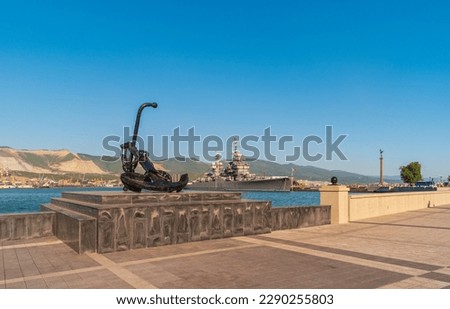 View of an anchor on the embankment of Novorossiysk with a cruiser in the port on the background, Russia.