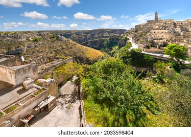 View of the ancient city of Matera, Italy in the Basilicata region, including the old town, tourist street and mountain path, Sasso Barisano tower and the steep ravine canyon below.