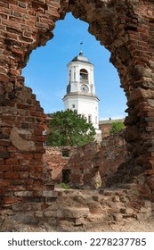 View of the ancient Clock Tower through the ruins of a medieval cathedral on a sunny July day. Vyborg, Russia