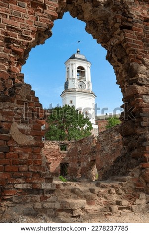 View of the ancient Clock Tower through the ruins of a medieval cathedral on a sunny July day. Vyborg, Russia