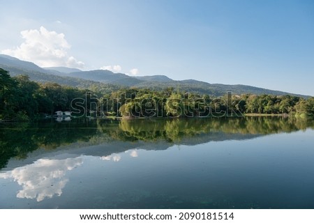 View of Ang Kaew reservoir with mountain and blue sky reflection on sunny day at Chiang Mai