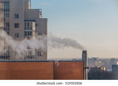 View Of Apartment House Pipe With Vapour At City Background And Blue Sky.