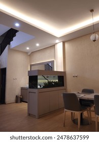 A view of the aquarium next to the dining table with gold colored lights so it looks aesthetic and luxurious
