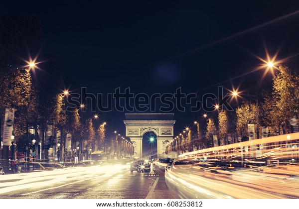View of Arc de Triomphe and the avenue\
Champs-Elysees illuminated at night. Famous touristic places and\
romantic travel destinations in Europe. Urban landscape with night\
traffic. Long exposure.\
Toned
