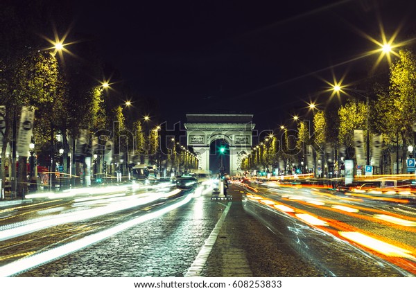 View of Arc de Triomphe and the avenue\
Champs-Elysees illuminated by night. Famous touristic places and\
romantic travel destinations in Europe. Urban landscape with night\
traffic. Long exposure.\
Toned